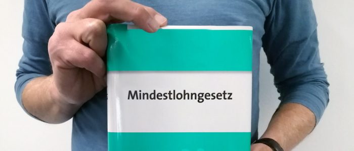 Mann hält Mindestlohngesetz in Händen.
