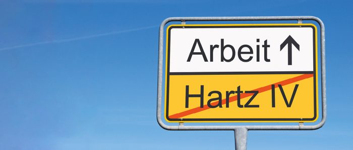 "Ortsende"-Verkehrsschild mit der Aufschrift "Hartz IV" (durchgestrichen) und "Arbeit" (nicht durchgestrichen)n