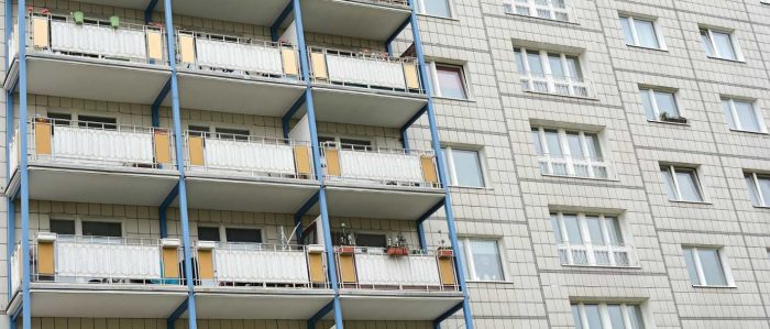 Trostlose Fassade eines Wohngebäudes. Die eine Hälfte der Wohnungen hat einen Balkon, die andere nicht.