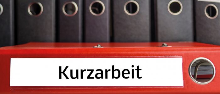 The picture shows several files on a shelf with the title "Kurzarbeit" (short time allowance)