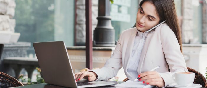 Junge Frau sitzt mit Laptop im Homeoffice und telefoniert.