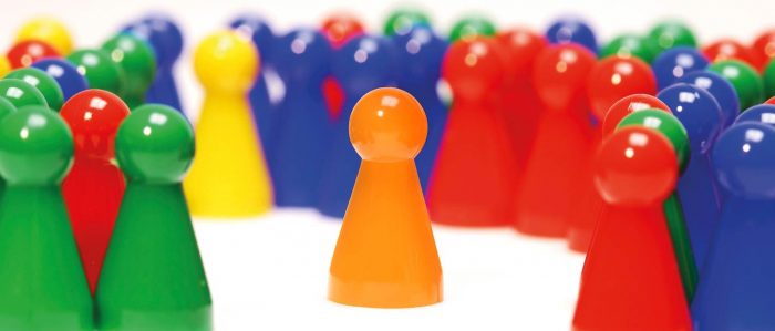 Orange Spielfigur wird von einer Vielzahl andersfarbiger Spielfiguren umringt.