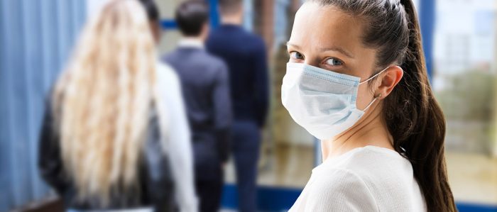 Gruppe von Schülern mit Mundschutz wartet vor einer Glastür.