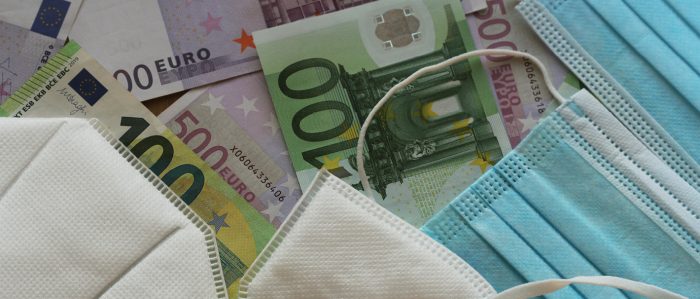 Verschiedene Mundschutzmasken liegen auf einem Tisch, auf dem 100-€, 200€- und 500€-Scheine ausgebreitet sind