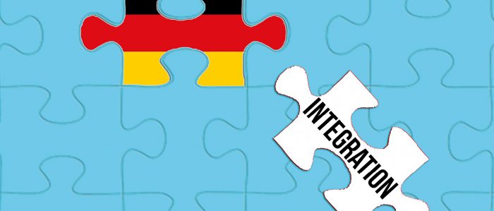 Puzzle mit einem Puzzleteil „Integration“ und einem Puzzleteil, das die deutschen Nationalfarben zeigt.