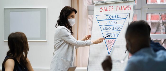 Eine Frau steht in einer Firma am Flipchart und hält einen Vortrag.