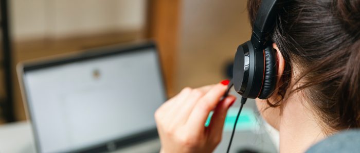 Frau sitzt mit Tablet und Headset im Homeoffice