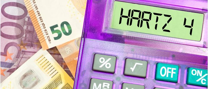 Taschenrechner, in dessen Display „Hartz IV“ steht, mit Geldscheinen im Hintergrund