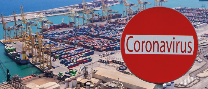 Blick auf Hafenterminal mit Containerschiffen. Im Vordergrund ein Schild mit der Aufschrift Coronavirus.