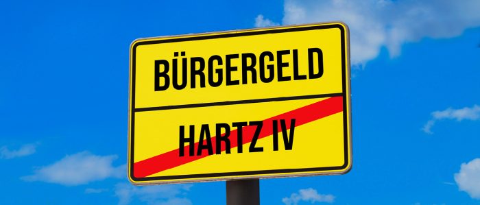 Gelbes Ortsschild, auf dem über einem durchgestrichenen „Hartz IV“ das Wort „Bürgergeld“ steht.