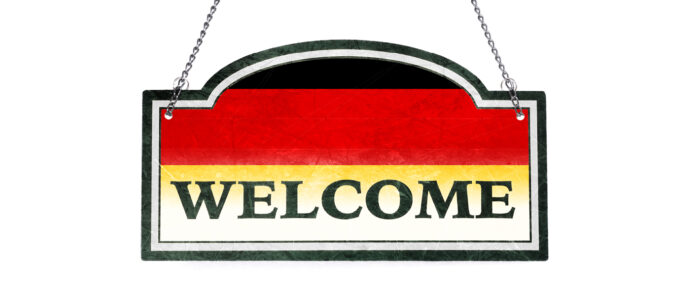 Schild mit den deutschen Nationalfarben im Hintergrund und der Aufschrift "Welcome"