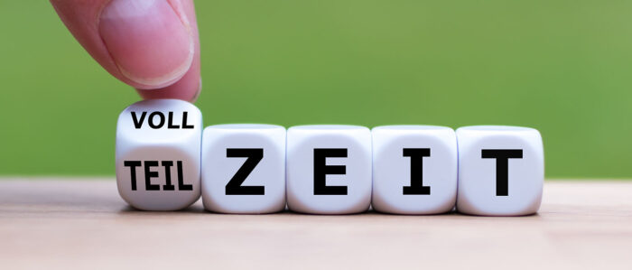 Eine Hand dreht den ersten Würfel einer Würfelreihe mit Buchstaben und ändert so das Wort "Vollzeit" in "Teilzeit" oder umgekehrt.