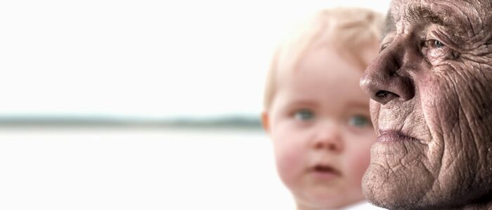 Das Bild zeigt das Gesichtsprofil eines alten Mannes und neben ihm schaut ihn ein Kind an.