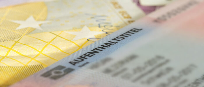 Nahaufnahme einer Aufenthaltserlaubnis für Deutschland, die auf Euro-Geldscheinen liegt.