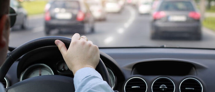 Aufnahme über die Schulter eines Autofahrers, der im Berufsverkehr fährt.
