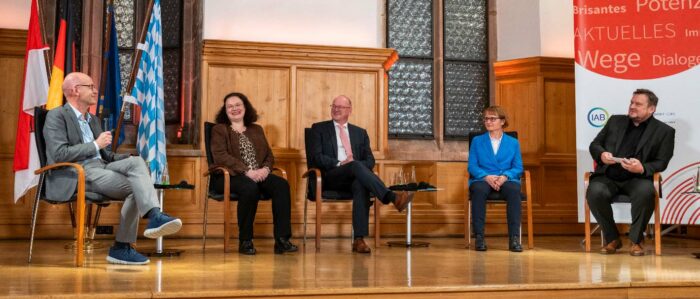 Die Podiumsgäste der Nürnberger Gespräche in der Totalen. Ulrich Walwei mit Mikrofon