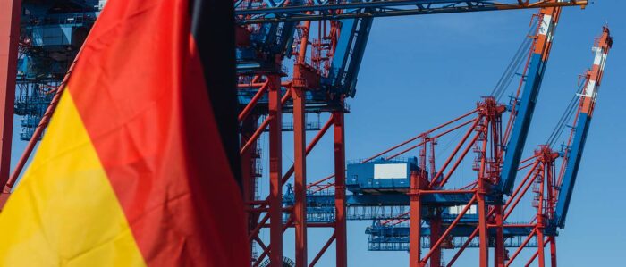 Deutsche Flagge bei Windstille vor einem Containerterminal.
