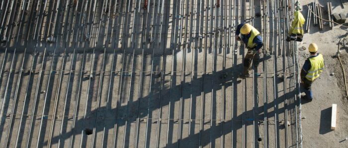 Zwei Bauarbeiter arbeiten auf einer Baustelle, Ansicht von oben Construction worker at a building site, top view.