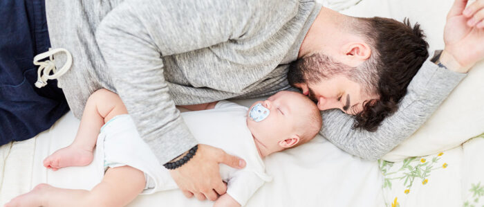 Vater kuschelt sich an sein schlafendes Baby