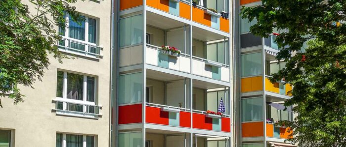 Fassade eines Mehrfamilienhauses mit verschiedenfarbigen Balkonen.